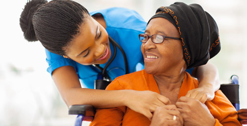 Lady hugging, from behind, an older lady in a wheelchair